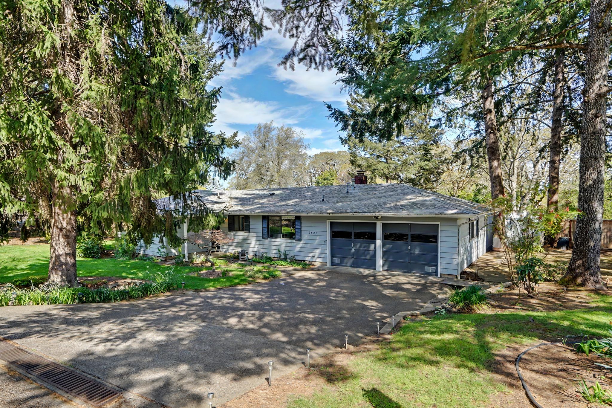 light gray home surrounded by trees and green grass