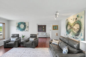 Open-concept living room with hardwood floors, large windows, and adjoining sitting area in Philomath, Oregon ranch home for sale.