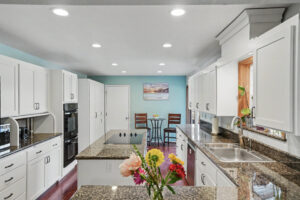Bright open-concept kitchen with white shaker cabinets, granite island, and stainless appliances in Philomath, Oregon ranch home for sale.